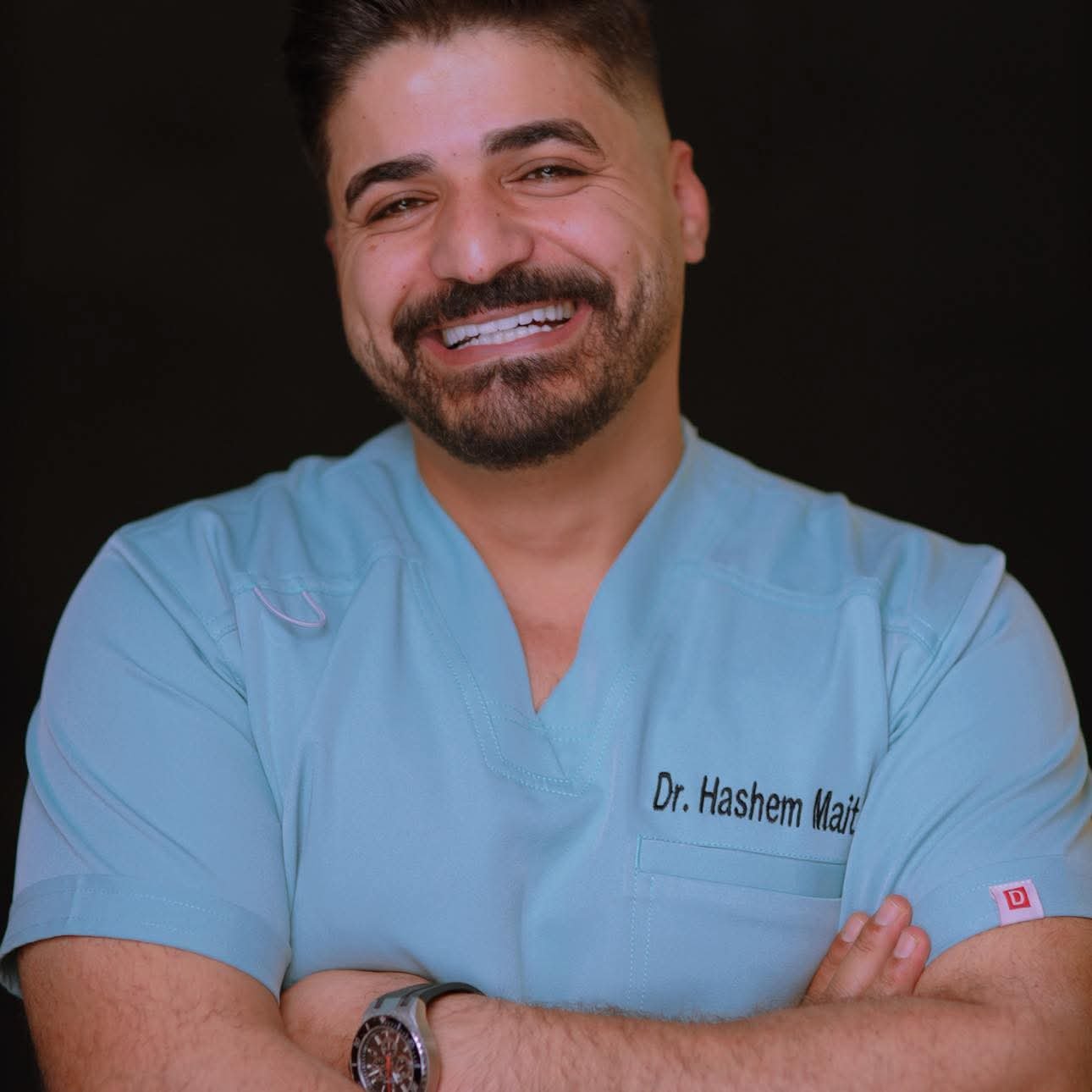 Dr. Hashem Maitah standing next to clinic logo